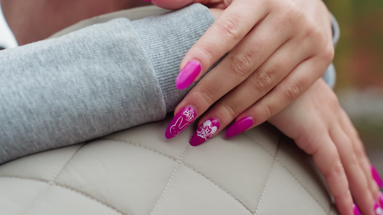 Close up of woman with bright purple nails hugging husband outdoors in casual attire, her hand gently resting on quilted jacket with blurred background