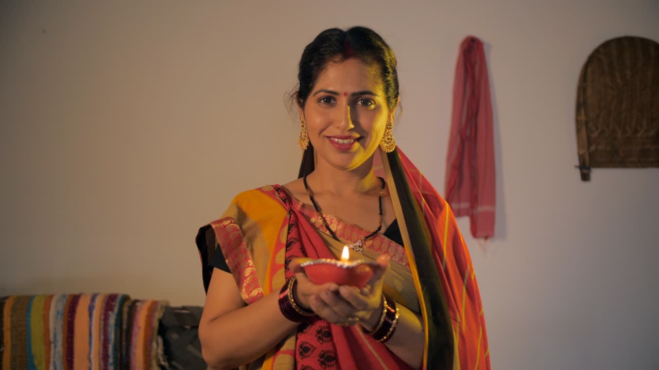 Ritratto di una bella donna indiana di villaggio che tiene in mano una Diya durante il festival di Diwali.