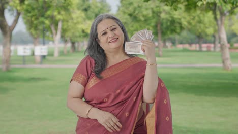 Happy-Indian-old-woman-using-money-as-fan-in-park