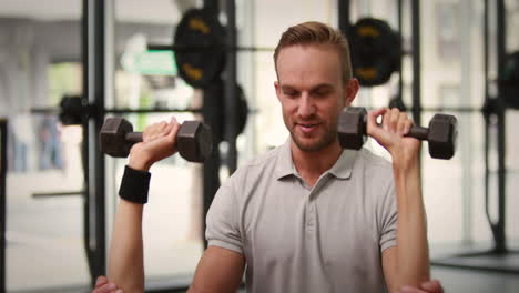 fit woman lifting dumbbells with trainer