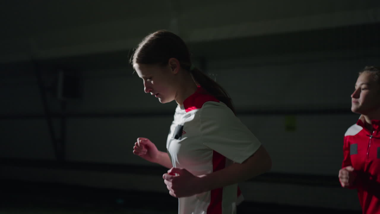 어린 여자 축구팀이 실내 훈련 중에 뛰고 있습니다.