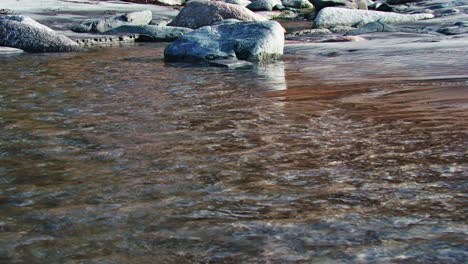 Klarer-Bach-Fließt-Durch-Steine-Felsbrocken-Am-Sandstrand