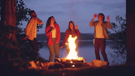 Friends Dancing Around a Campfire by the Lake at Night