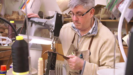 bespoke shoemaker stitching together leather pieces for shoe