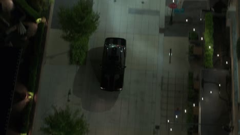 Drone-footage-of-a-Black-Sports-Car-driving-through-downtown-at-night