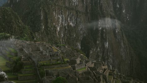 a slow time lapse of clouds drifting over machu picchu, peru, revealing its ancient ruins, zoom out