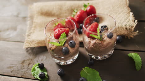 video of chocolate pudding with strawberries and bluberries on a wooden surface