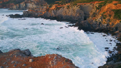 rocky shore stormy ocean foaming. drone waves hitting dangerous volcanic cliffs