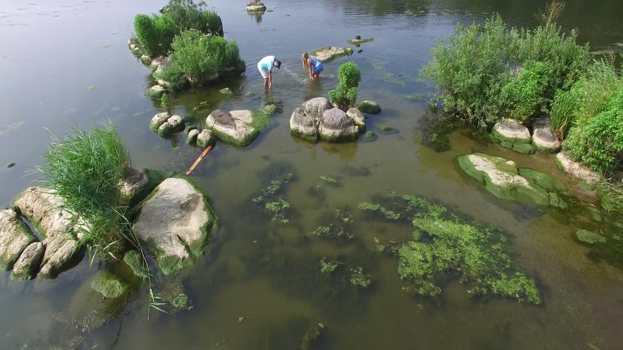 Couple Resting On River Bank. Aerial shot of a smiling couple resting on river bank in nature