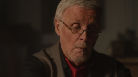 old passionate man put on the glasses in his office at night