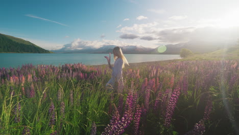 woman walking through fantasy scenery in magical flower field at alpine lake