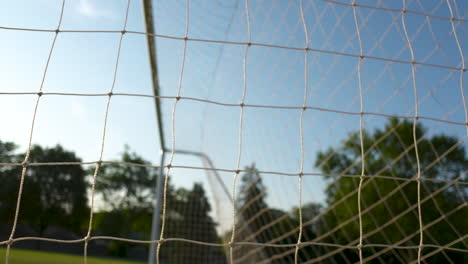de cerca, mirando a través de una red de fútbol al sol de la mañana