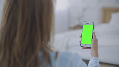 Mujer-Usando-Y-Mirando-La-Pantalla-Verde-Del-Teléfono-Inteligente-En-Casa.-La-Joven-Sostiene-Un-Teléfono-Inteligente-Con-Pantalla-Verde-Por-La-Noche.