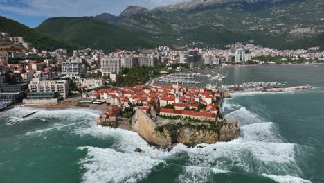sea waves crashing on the shores of budva old town aerial establishing