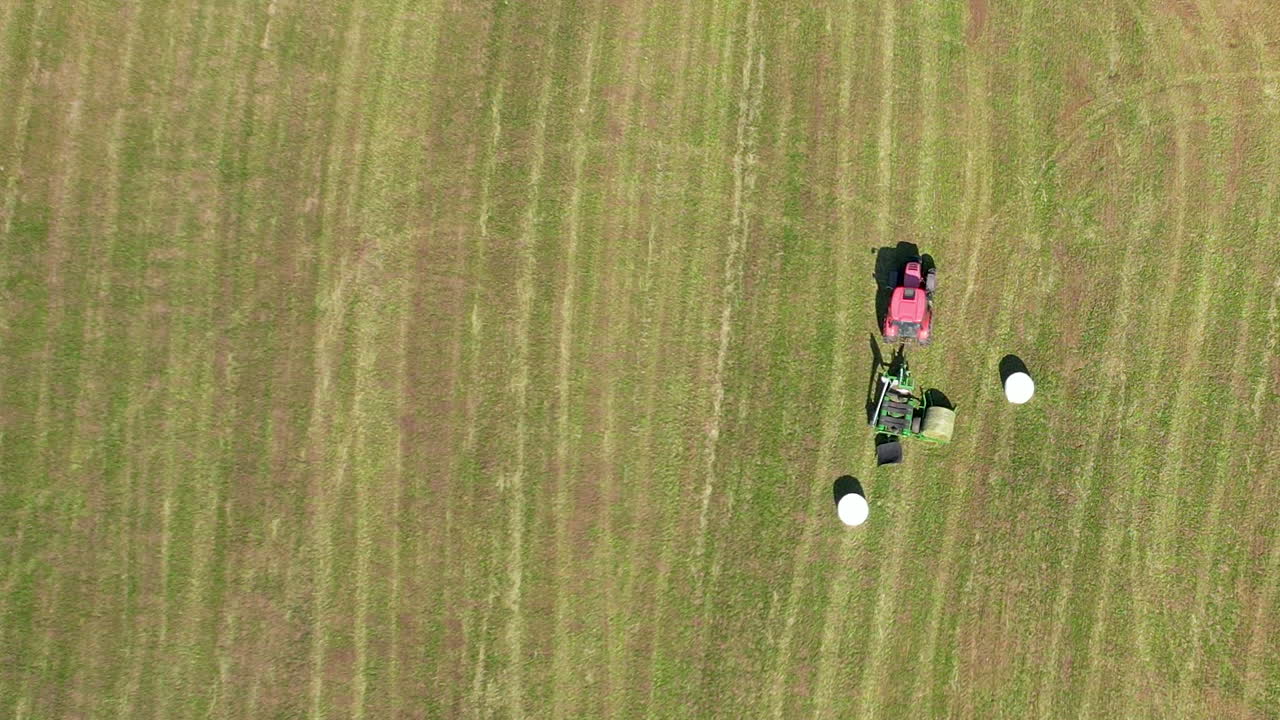 농장에서 흰색 플라스틱 필름으로 건초 베일을 포장하는 농업용 트랙터의 상위 뷰