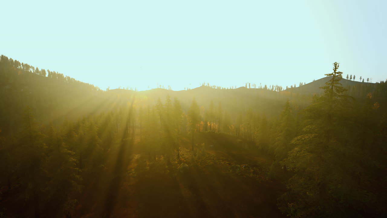 Gentle sunrise casting warm glow over layered ridges and valleys