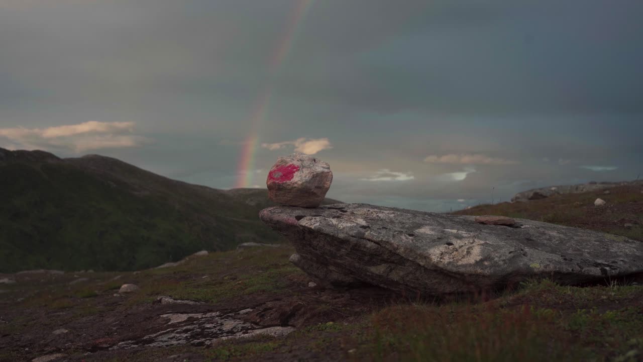 암 ⁇  하이커가 반려견과 함께 바위와 무지개를 가진 산악 풍경에서 트레킹하고 있습니다.