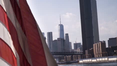 waving american flag on the boat with a view from east river of manhattan downtow- financial district- one world trade center
