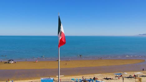 Vista-De-Un-Dron-Volando-Hacia-Adelante-Sobre-Un-Muelle-Que-Muestra-La-Bandera-Mexicana