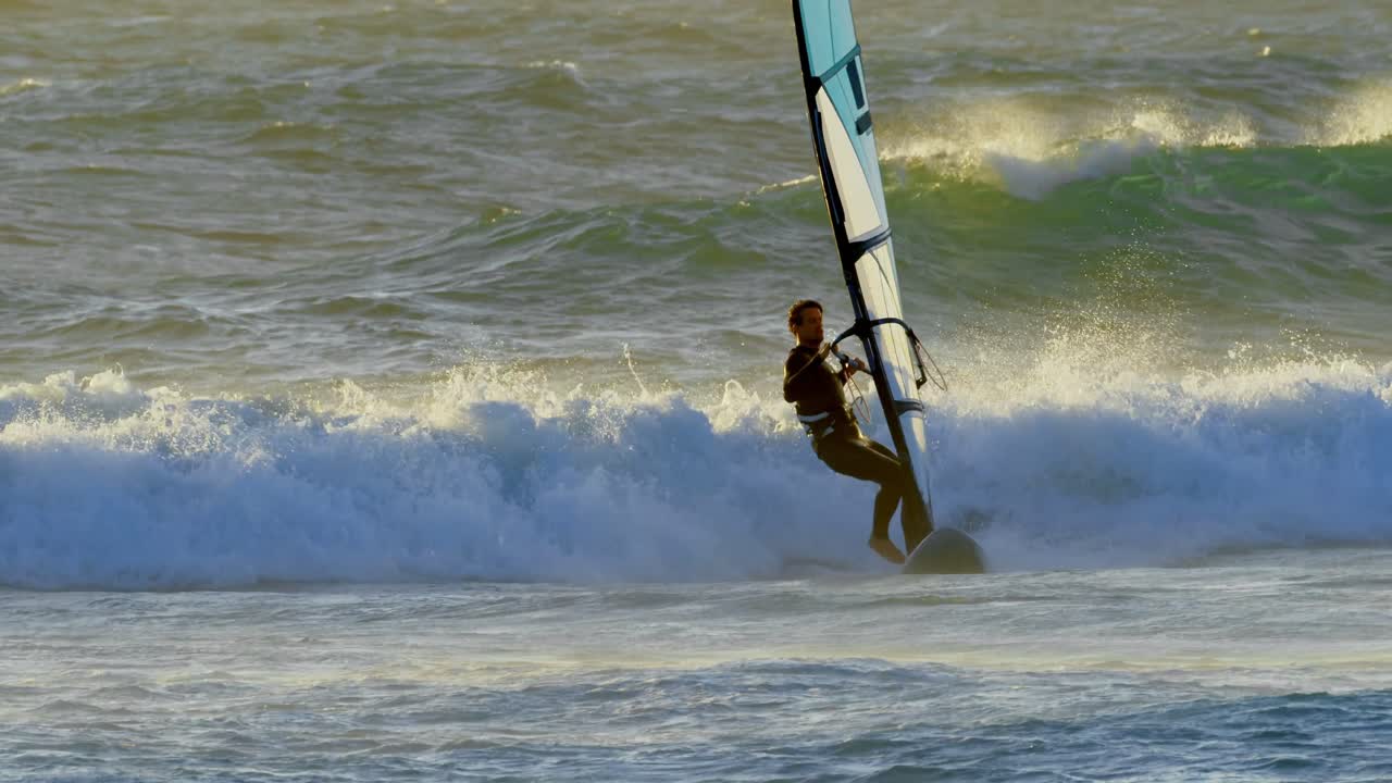 surfista masculino haciendo windsurf en la playa 4k