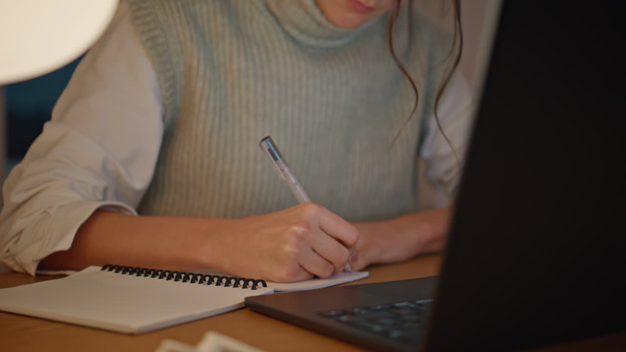 Closeup evening woman writing notebook home table. Unknown lady planning tasks