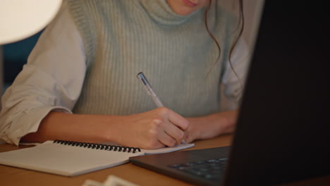 closeup noche mujer escribiendo cuaderno mesa de casa. señora desconocida tareas de planificación