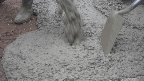 primer plano de hormigón húmedo que se vierte en el suelo mientras los trabajadores pavimentan una calle