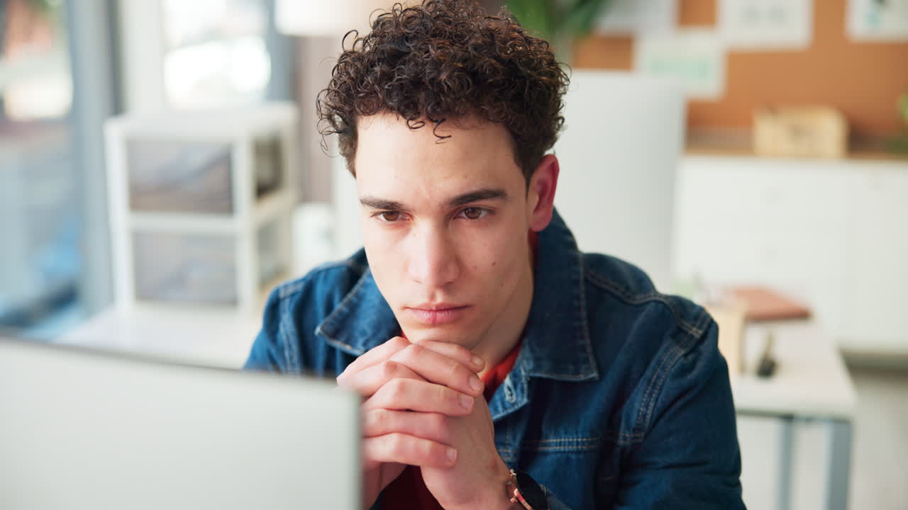 Young Man Concentrating While Working on Laptop in Office