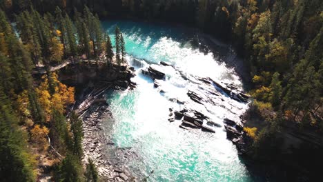 flying down aerial zoom in shot of rearguard falls drone flying over forest towards the waterfalls on a sunny day in autumn in a forest environment and the fraser river