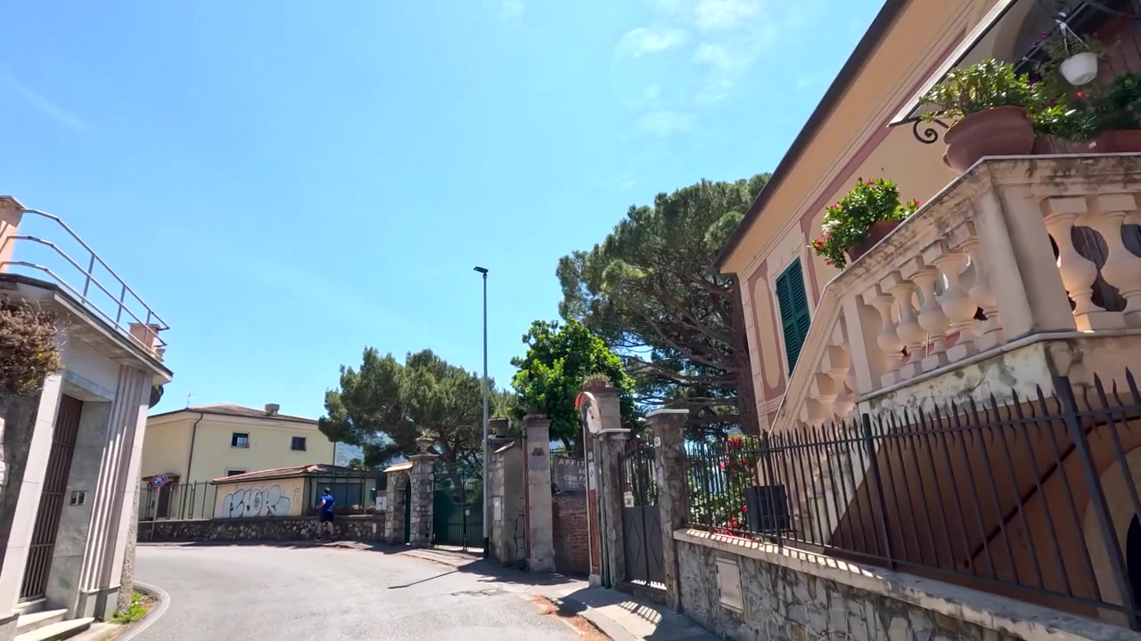 Una carrellata dal basso passa davanti a vivaci ville mediterranee lungo una strada costiera tortuosa