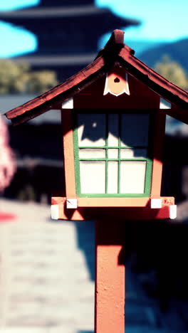 close-up of a red japanese lantern with a pagoda in the background