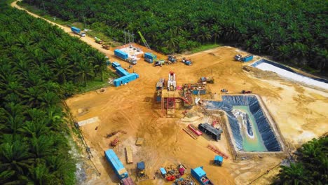 cinematic drone footage of onshore drilling rig equipment structure for oil exploration and exploitation in the middle of jungle surrounded by palm oil trees during sunset and high oil price