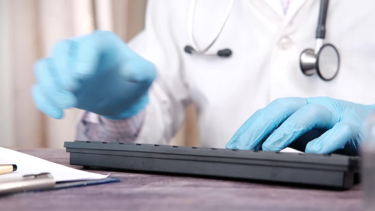 médico trabajando en la computadora con guantes
