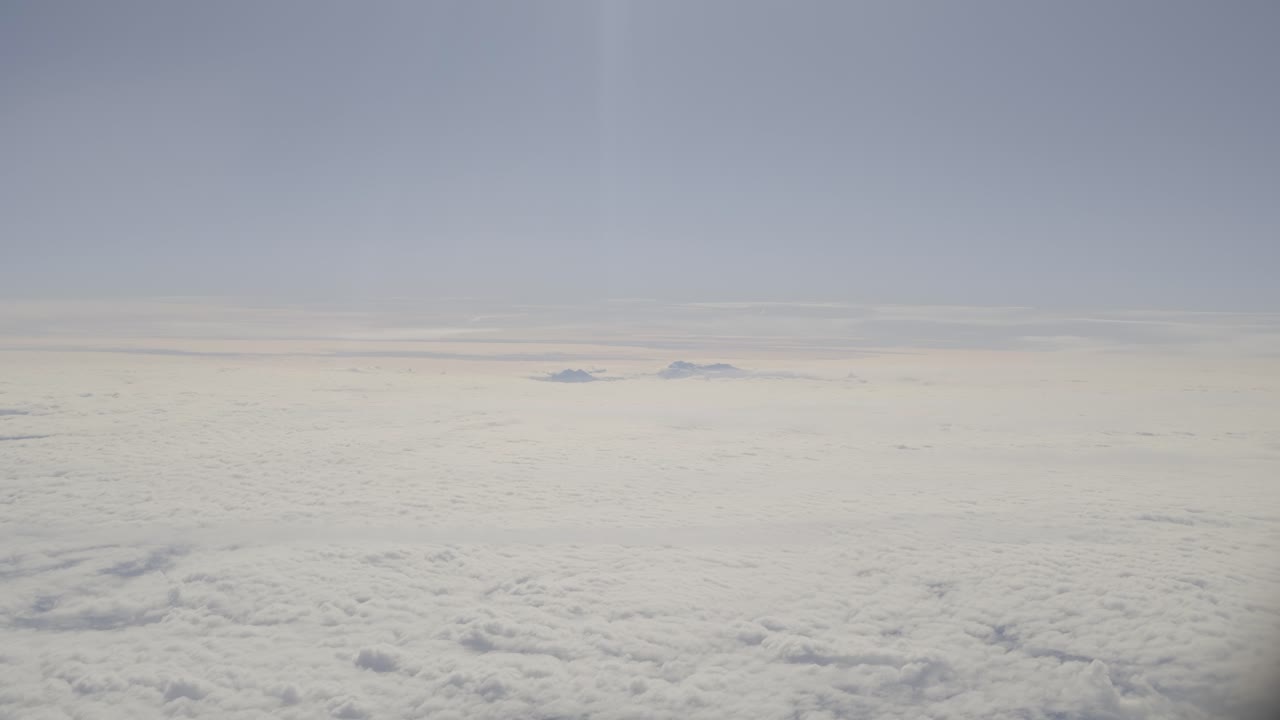 Snow-capped peaks breaking through dense cloud cover under clear blue sky