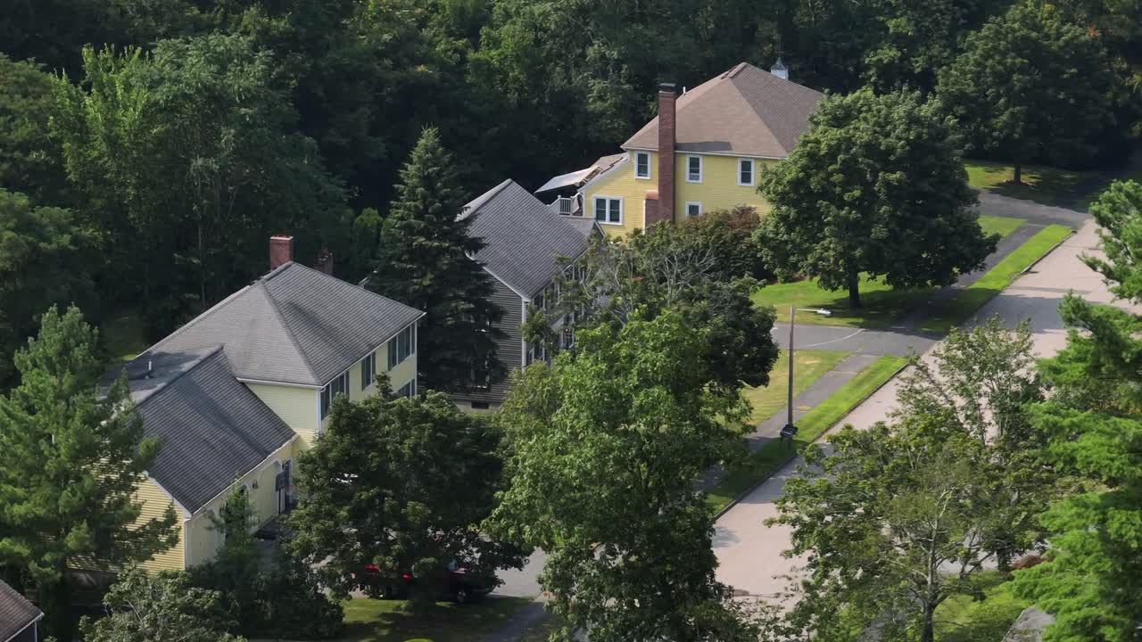 American houses in different colors and long red chimney on side wall. Aerial view. Sunny day with green trees in summer. Massachusetts, USA