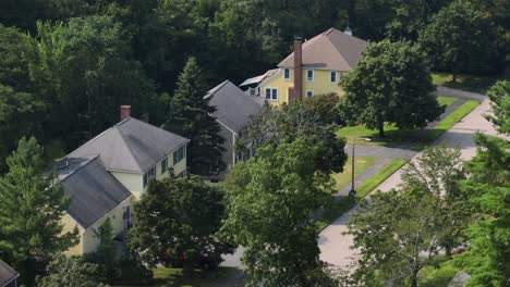 American houses in different colors and long red chimney on side wall. Aerial view. Sunny day with green trees in summer. Massachusetts, USA