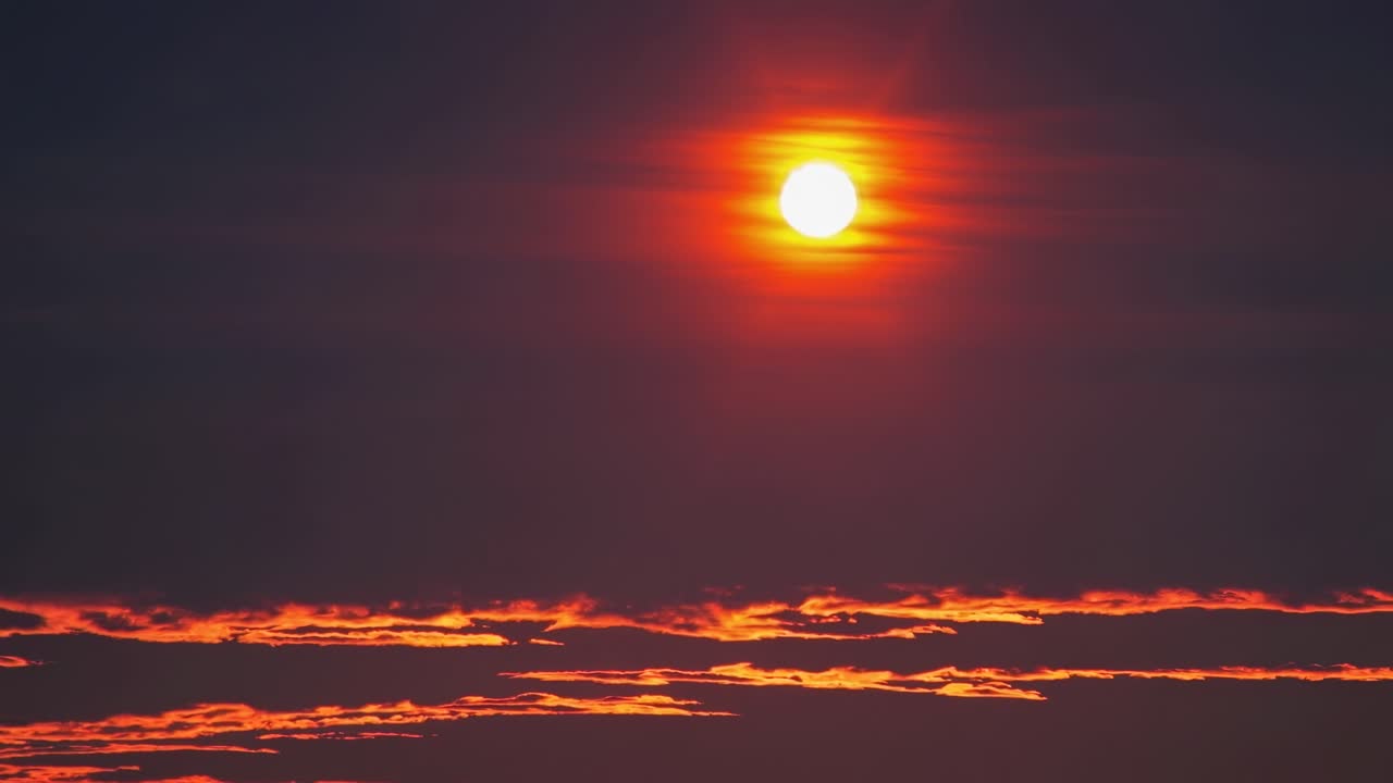 A mesmerizing sunset video with a low-angle shot capturing the vibrant orange sun and dark clouds