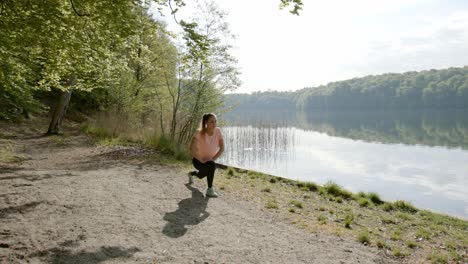 woman lunging near lake and woods on sunny day