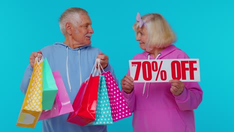 Senior-grandparents-showing-shopping-bags-and-Up-To-70-Percent-Off-banner-text,-Black-Friday-holiday