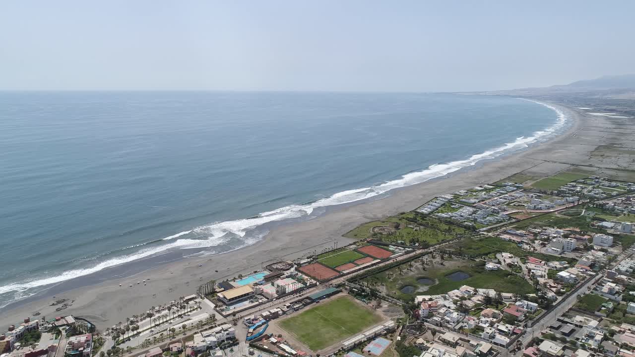 Stunning aerial panorama of a vast beach with rolling waves and a coastal town. Ideal for travel, real estate, and marketing visuals. Mollendo, Arequipa, Peru.