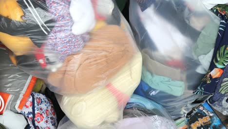 donación de pilas de ropa y juguetes en bolsas de plástico