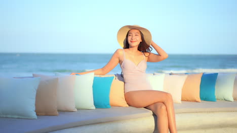 수영복을 입은 매력적인 여성이 바다를 배경으로 벤치에 앉아 있습니다.