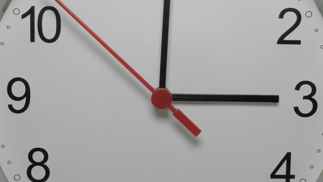 Primo piano di un quadrante di orologio bianco che suggerisce il passare del tempo. Orologio rotondo bianco con numeri arabi neri.
