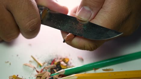 Footage-of-hands-slowly-sharpening-a-pencil-and-some-coloured-pencils-with-a-sharp-knife