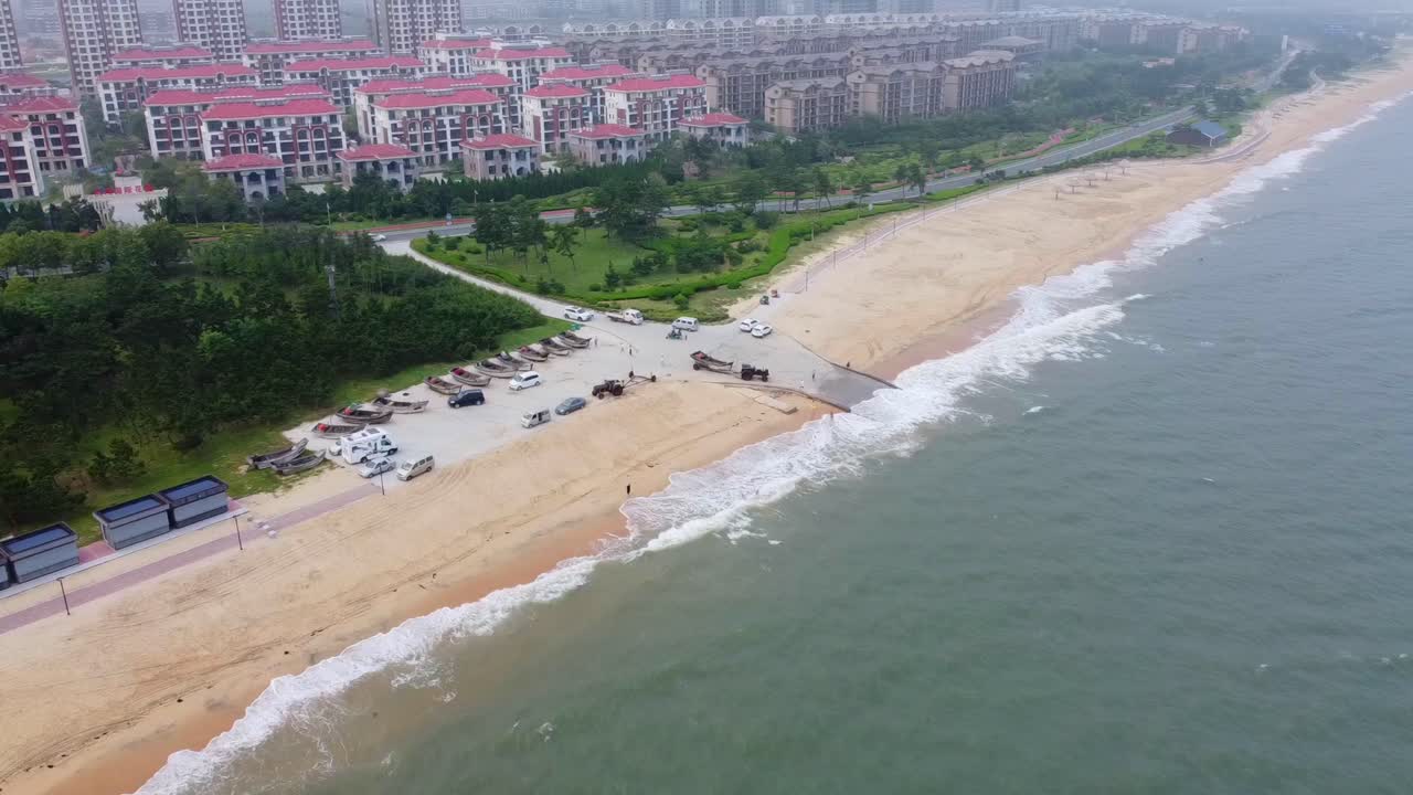 High aerial panoramic view of sandy beach with green promenade garden and cityscape background