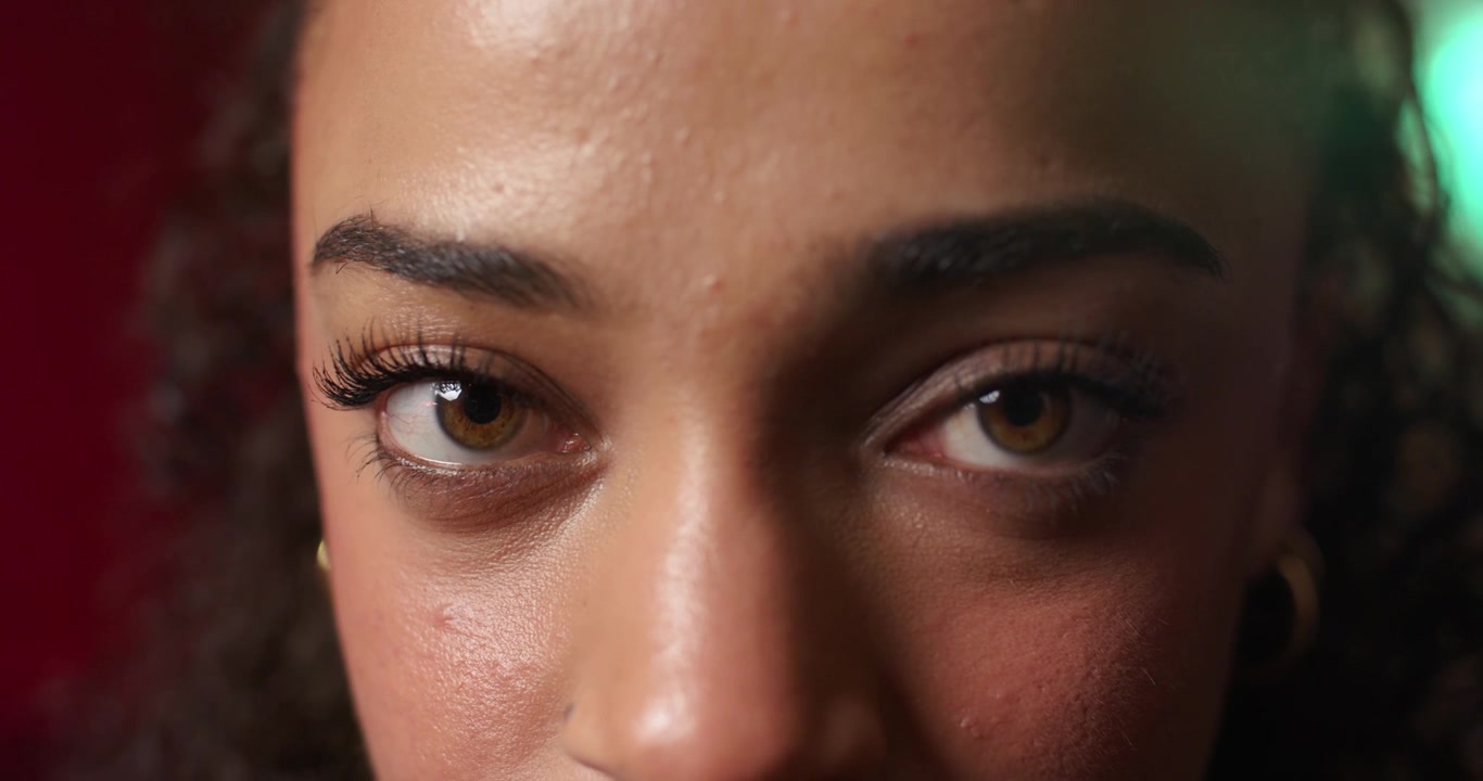 African American woman starting closed eyes opening eyes focusing camera left lash gold-hoop studio