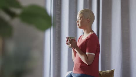 happy biracial woman drinking coffee at home in slow motion