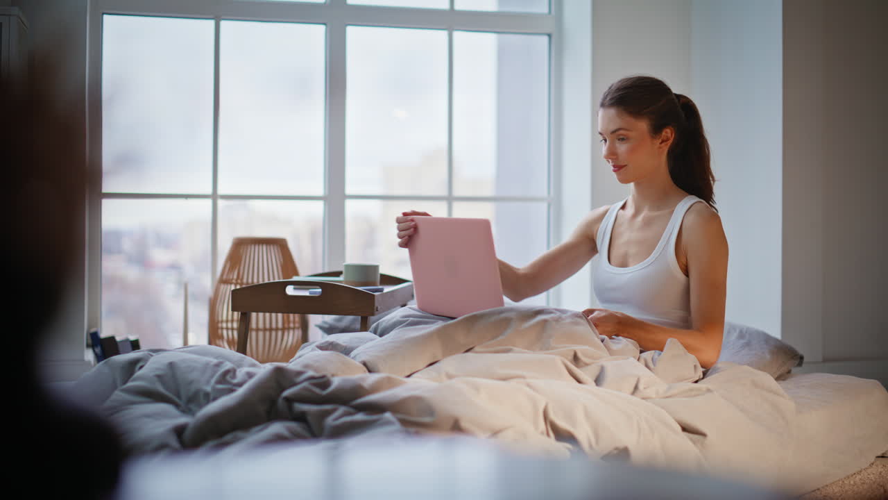 Signora che chiude il laptop a letto dopo aver terminato la lettura delle email la mattina presto. Freelance al lavoro.