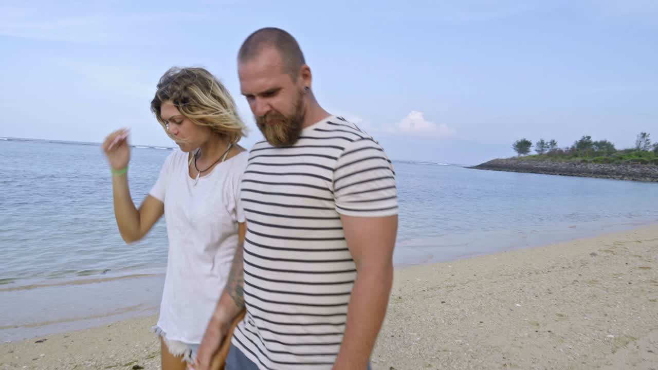 pareja besándose y abrazándose mientras caminan por la playa