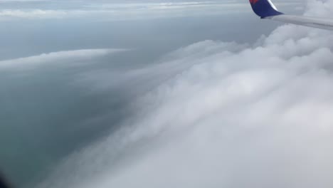 view of clouds in the sky from the window of a plane flying over the ocean.